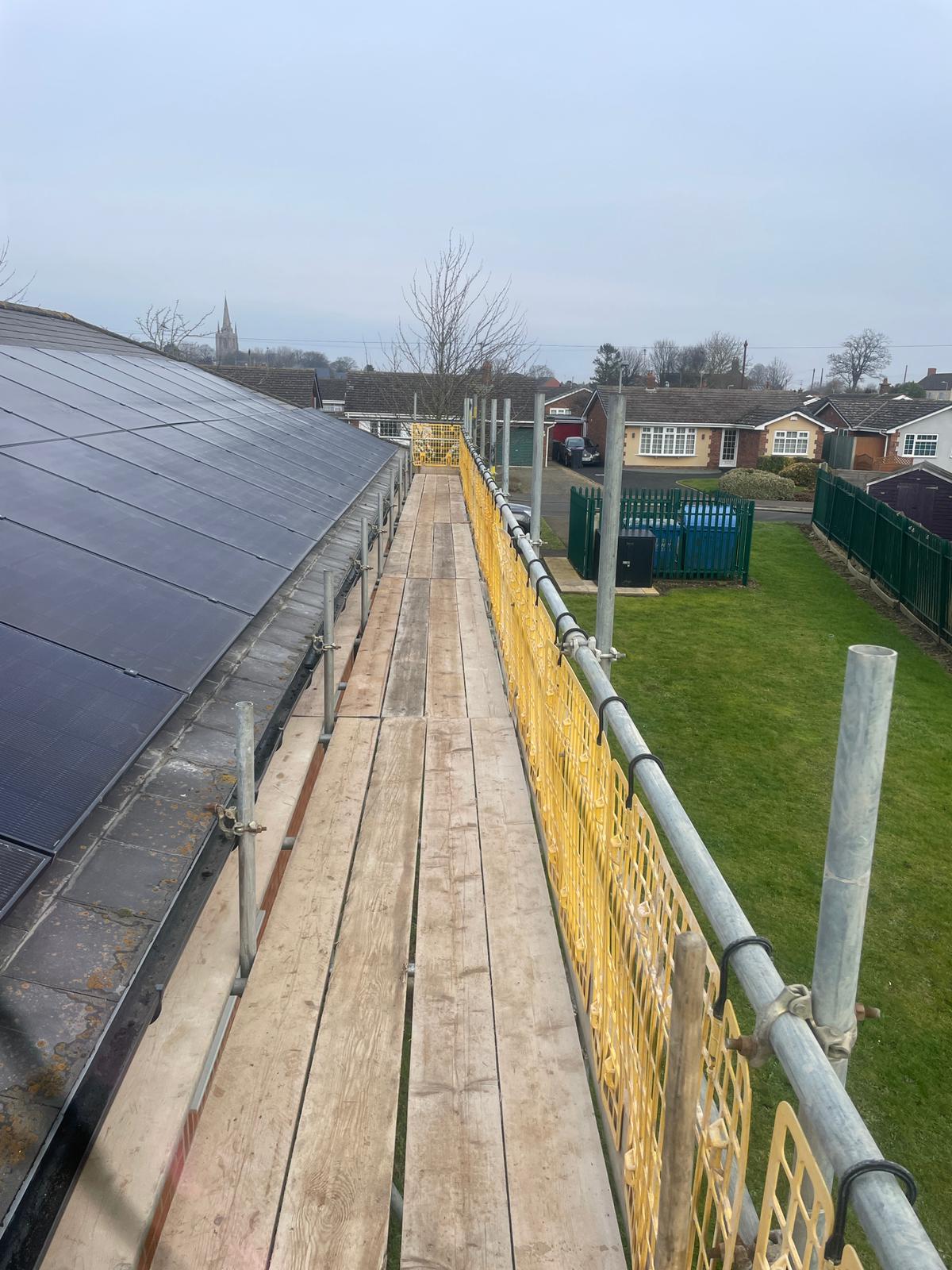 Commercial solar installer working on roof walkway during panel installation at medical centre